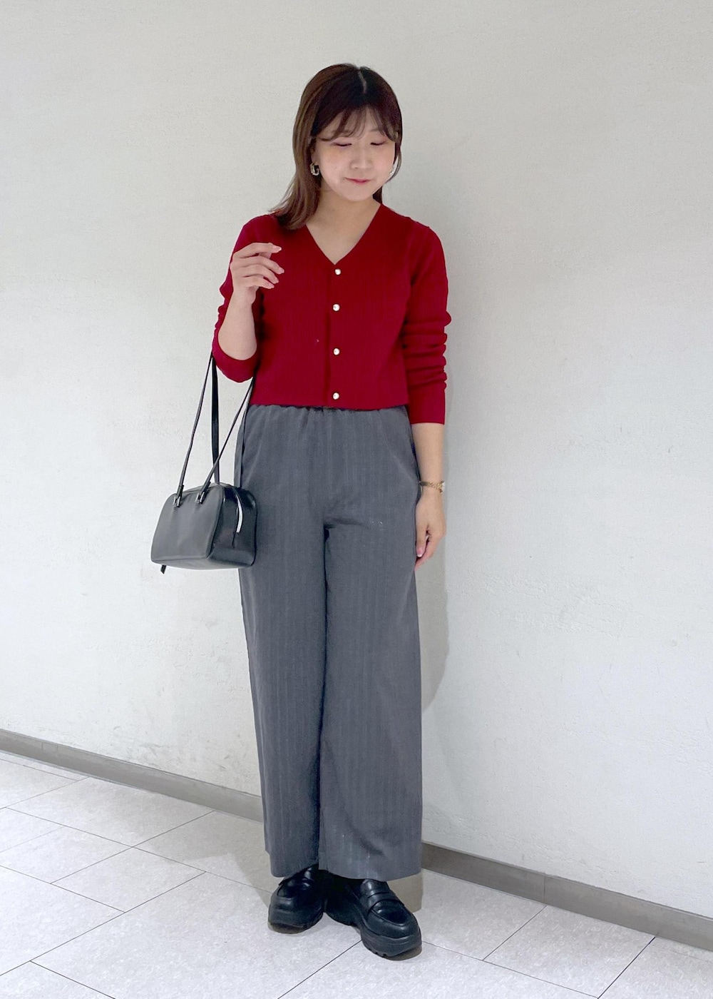 レッド系のカーディガン/ボレロ、グレー系のその他パンツ、ブラック系のボストンバッグを着用したレディースの秋コーディネートの2枚目の写真