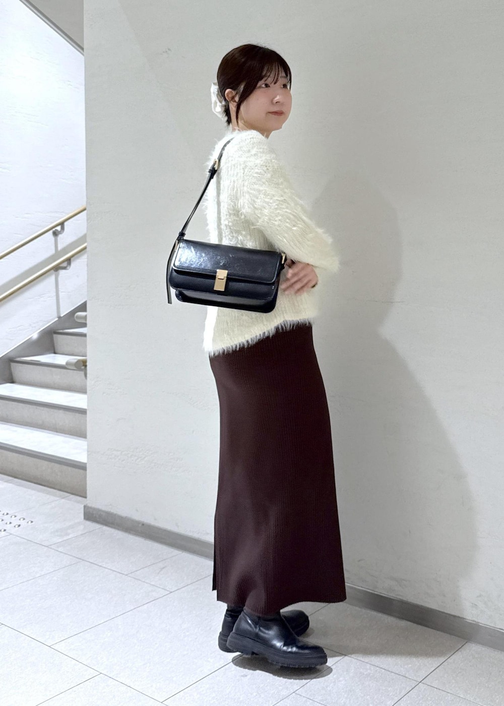 ブラック系のショルダーバッグ、ブラウン系のその他アウター、ホワイト系のニット/セーターを着用したレディースの冬コーディネートの8枚目の写真