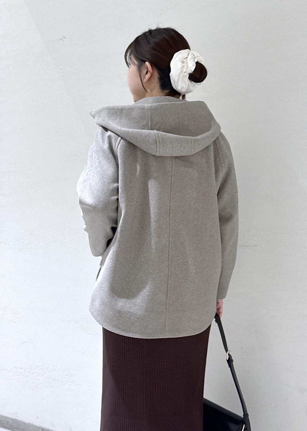 ブラック系のショルダーバッグ、ブラウン系のその他アウター、ホワイト系のニット/セーターを着用したレディースの冬コーディネートの6枚目の写真