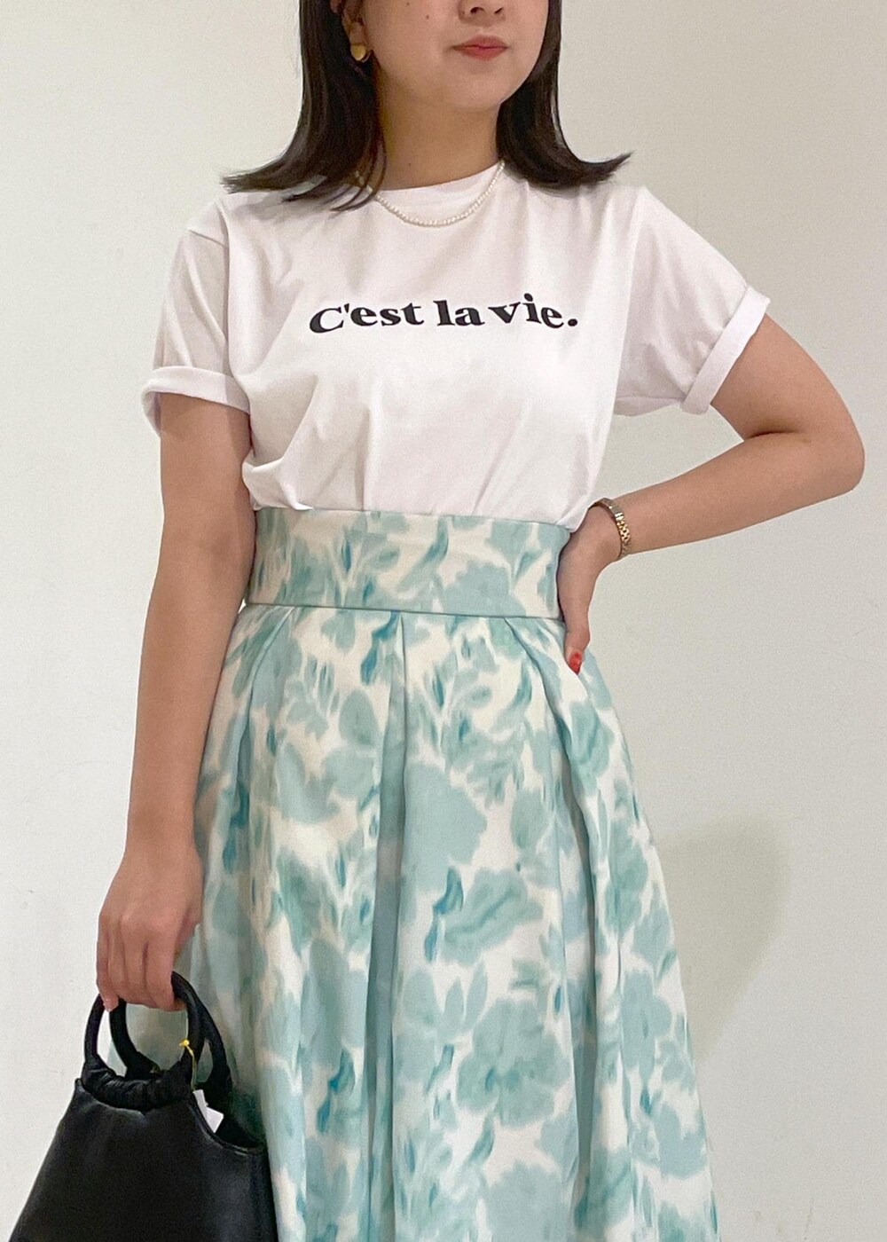 ブルー系のスカート、ブラック系のショルダーバッグ、ホワイト系のTシャツ/カットソーを着用したレディースの夏コーディネートの5枚目の写真