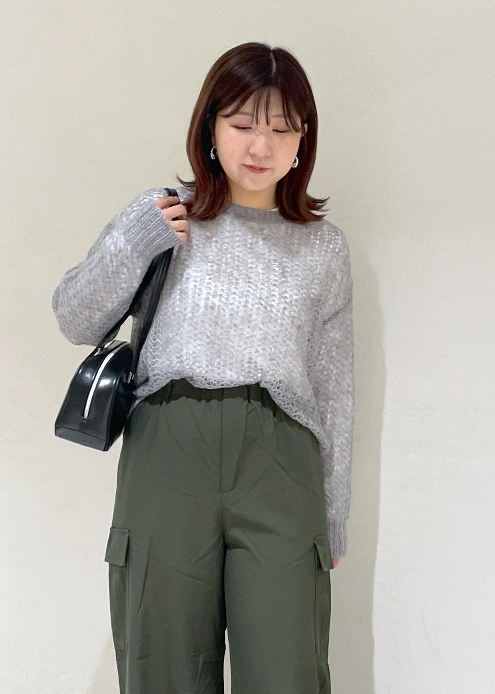 グレー系のニット/セーター、グリーン系のカーゴパンツ、ブラック系のボストンバッグを着用したレディースの秋コーディネートの6枚目の写真