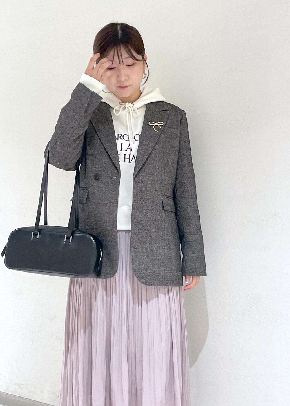 ホワイト系のパーカー、ブラック系のテーラードジャケット、ブラック系のボストンバッグを着用したレディースの秋コーディネートの6枚目の写真