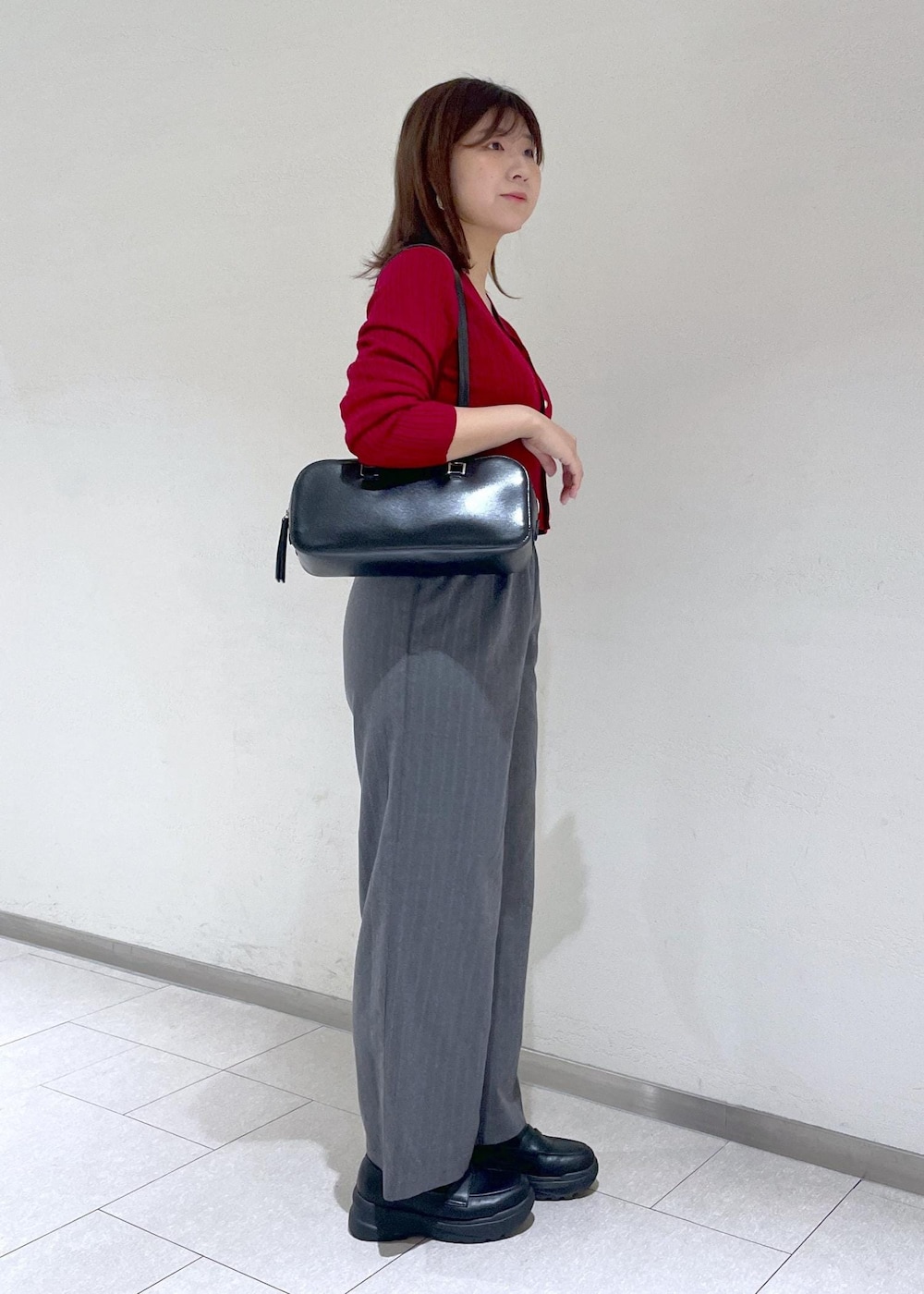 レッド系のカーディガン/ボレロ、グレー系のその他パンツ、ブラック系のボストンバッグを着用したレディースの秋コーディネートの4枚目の写真