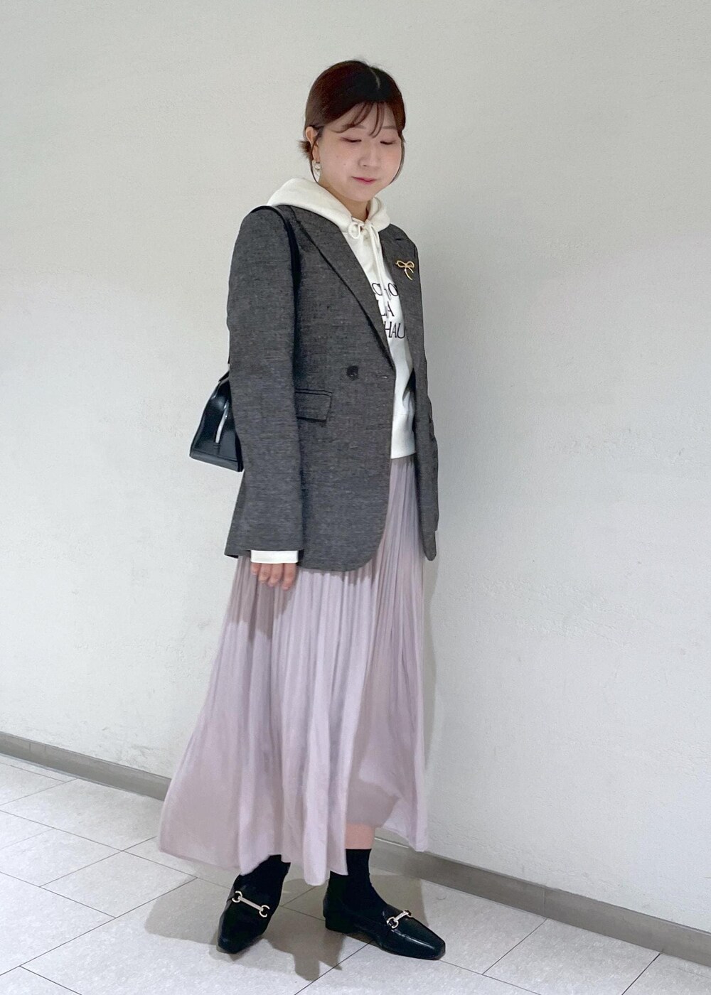 ホワイト系のパーカー、ブラック系のテーラードジャケット、ブラック系のボストンバッグを着用したレディースの秋コーディネートの3枚目の写真