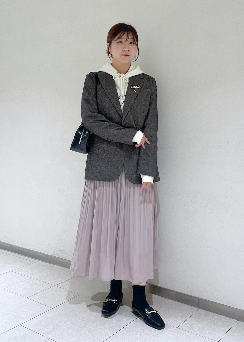 ホワイト系のパーカー、ブラック系のテーラードジャケット、ブラック系のボストンバッグを着用したレディースの秋コーディネートの2枚目の写真