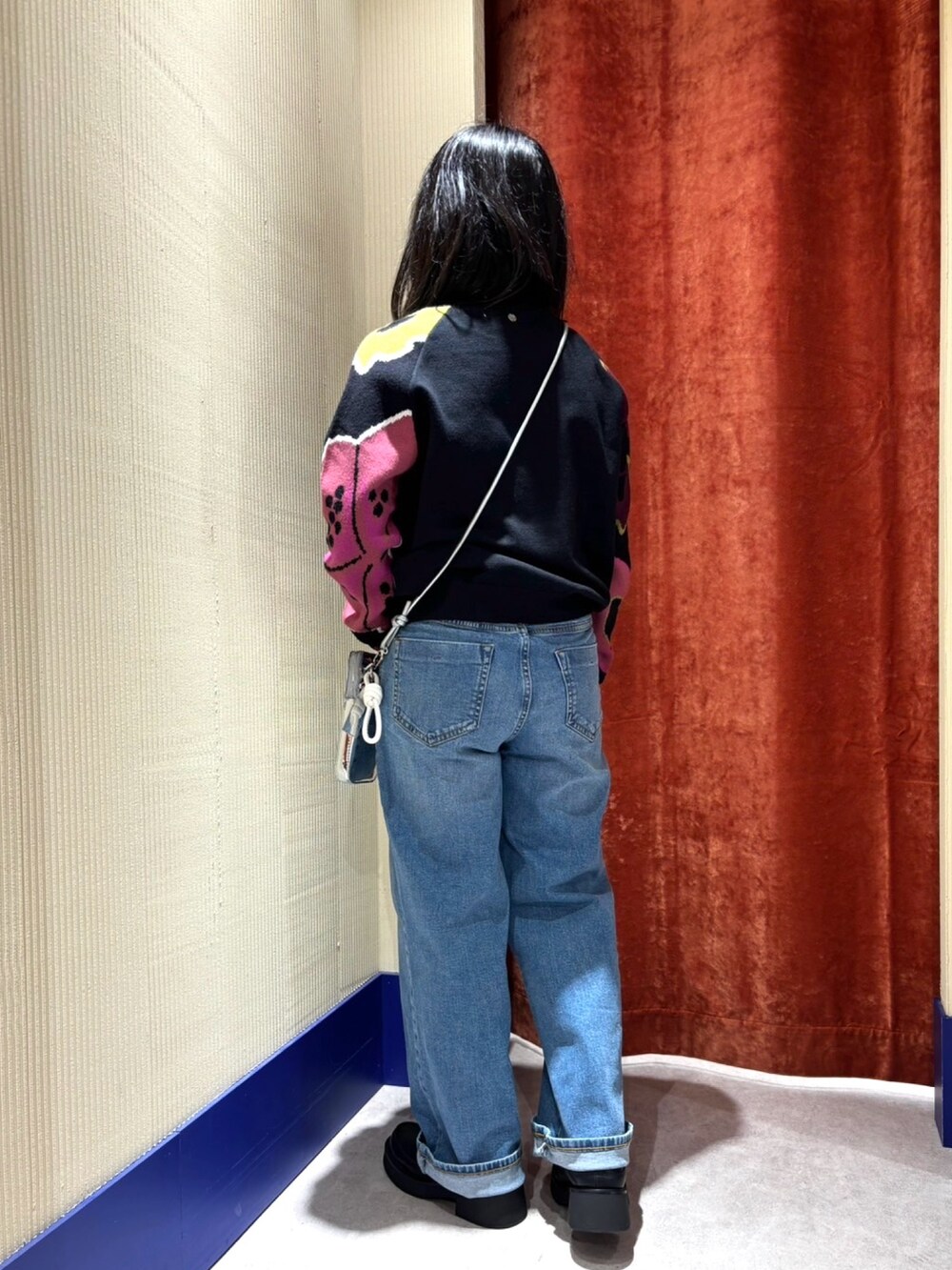 ブラック系のニット/セーター、ブルー系のデニムパンツ、シルバー系の財布を着用したレディースの秋コーディネートの2枚目の写真