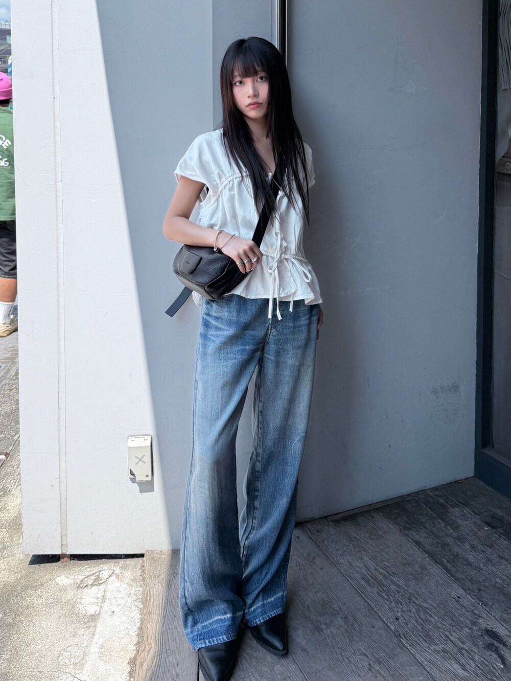 ブルー系のパンツ、ブラック系のブーツ、ホワイト系のトップスを着用したレディースの夏コーディネートの2枚目の写真