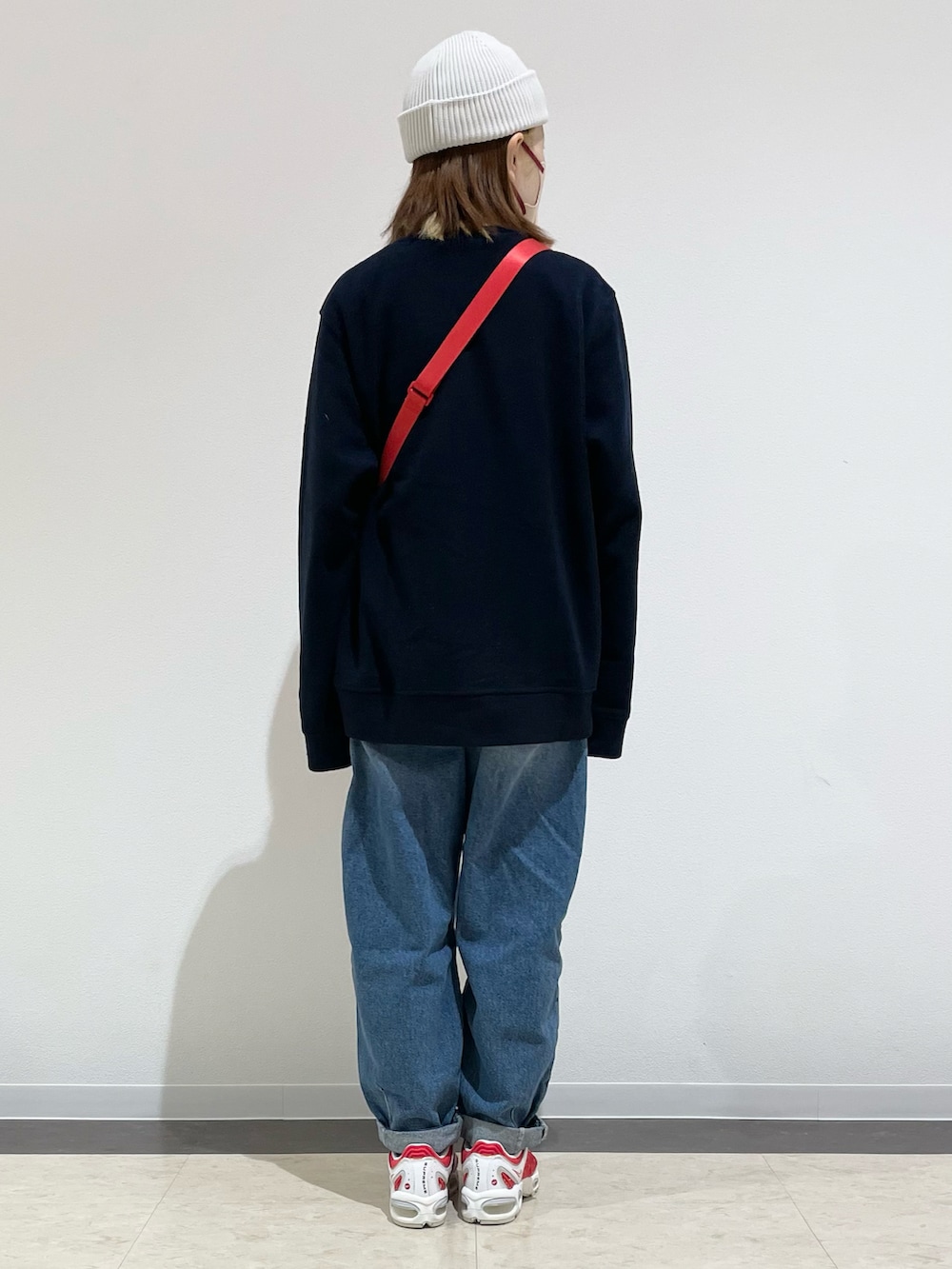 ブルー系のトップス、レッド系のショルダーバッグ、ブルー系のデニムパンツを着用したレディースの冬コーディネートの2枚目の写真