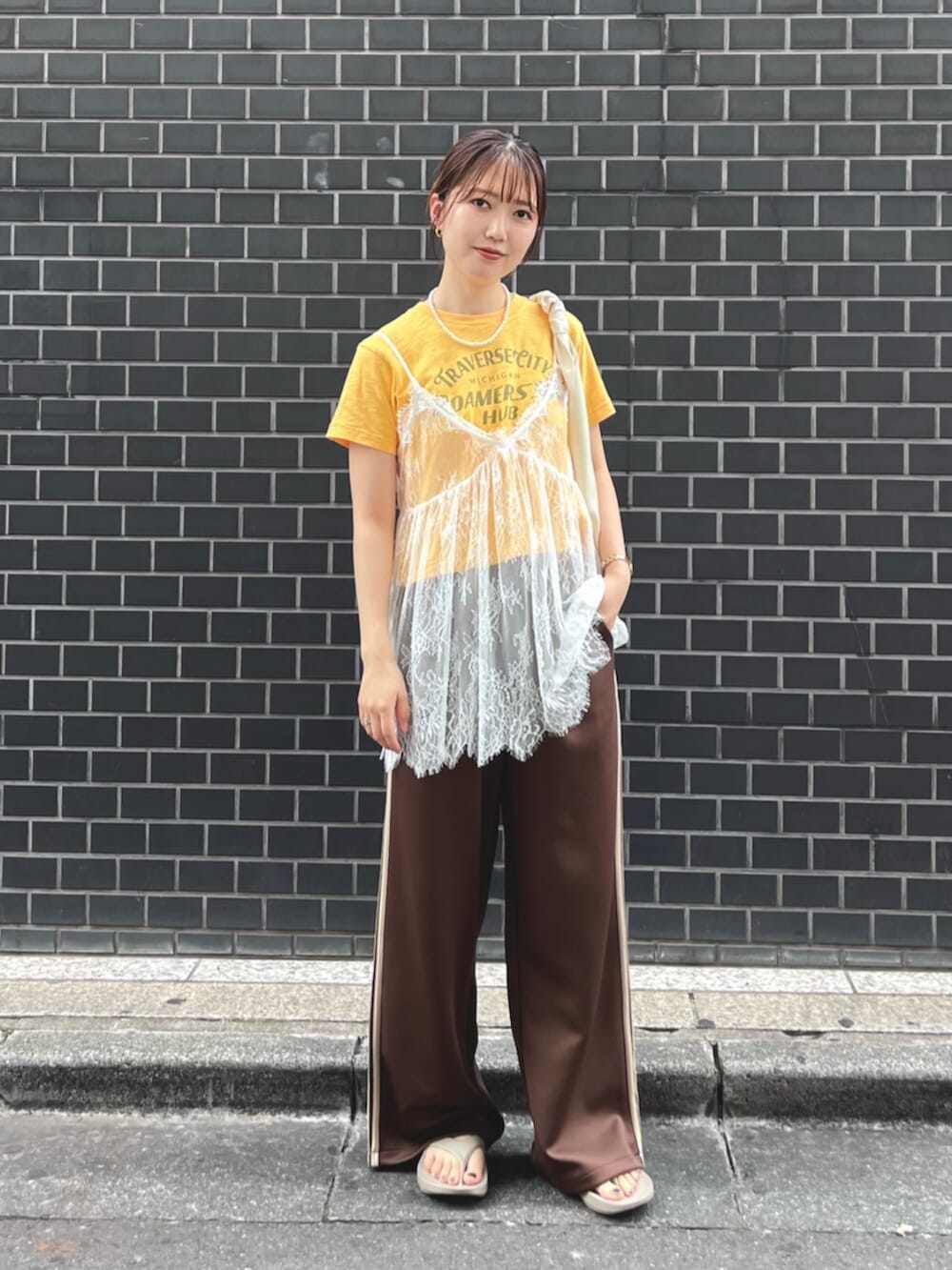 イエロー系のTシャツ/カットソー、ホワイト系のキャミソール、ホワイト系のハンドバッグを着用したレディースの夏コーディネートの2枚目の写真