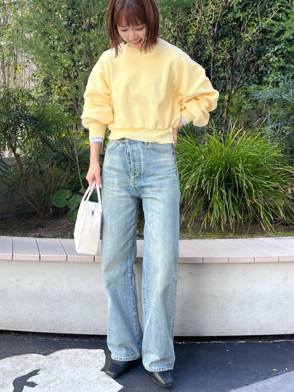 イエロー系のニット/セーター、ホワイト系のボストンバッグ、ブルー系のデニムパンツを着用したレディースの冬コーディネートの5枚目の写真