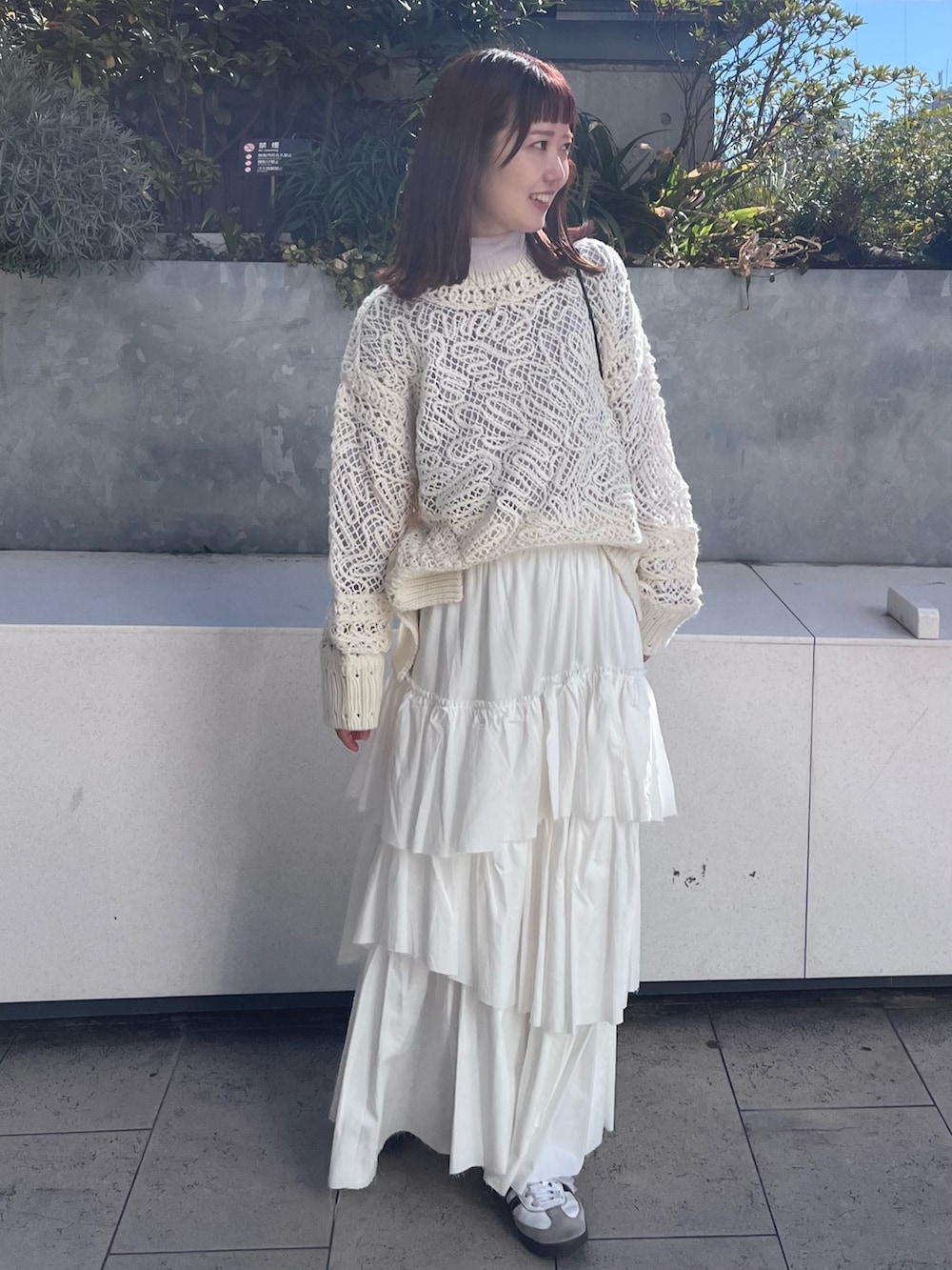 ホワイト系のニット/セーター、ホワイト系のスカート、パープル系のTシャツ/カットソーを着用したレディースの冬コーディネートの2枚目の写真