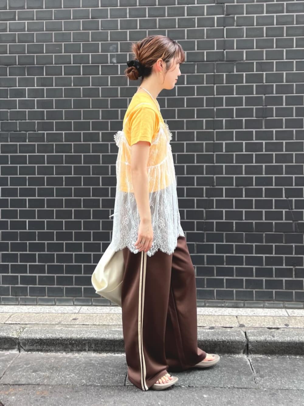 イエロー系のTシャツ/カットソー、ホワイト系のキャミソール、ホワイト系のハンドバッグを着用したレディースの夏コーディネートの3枚目の写真