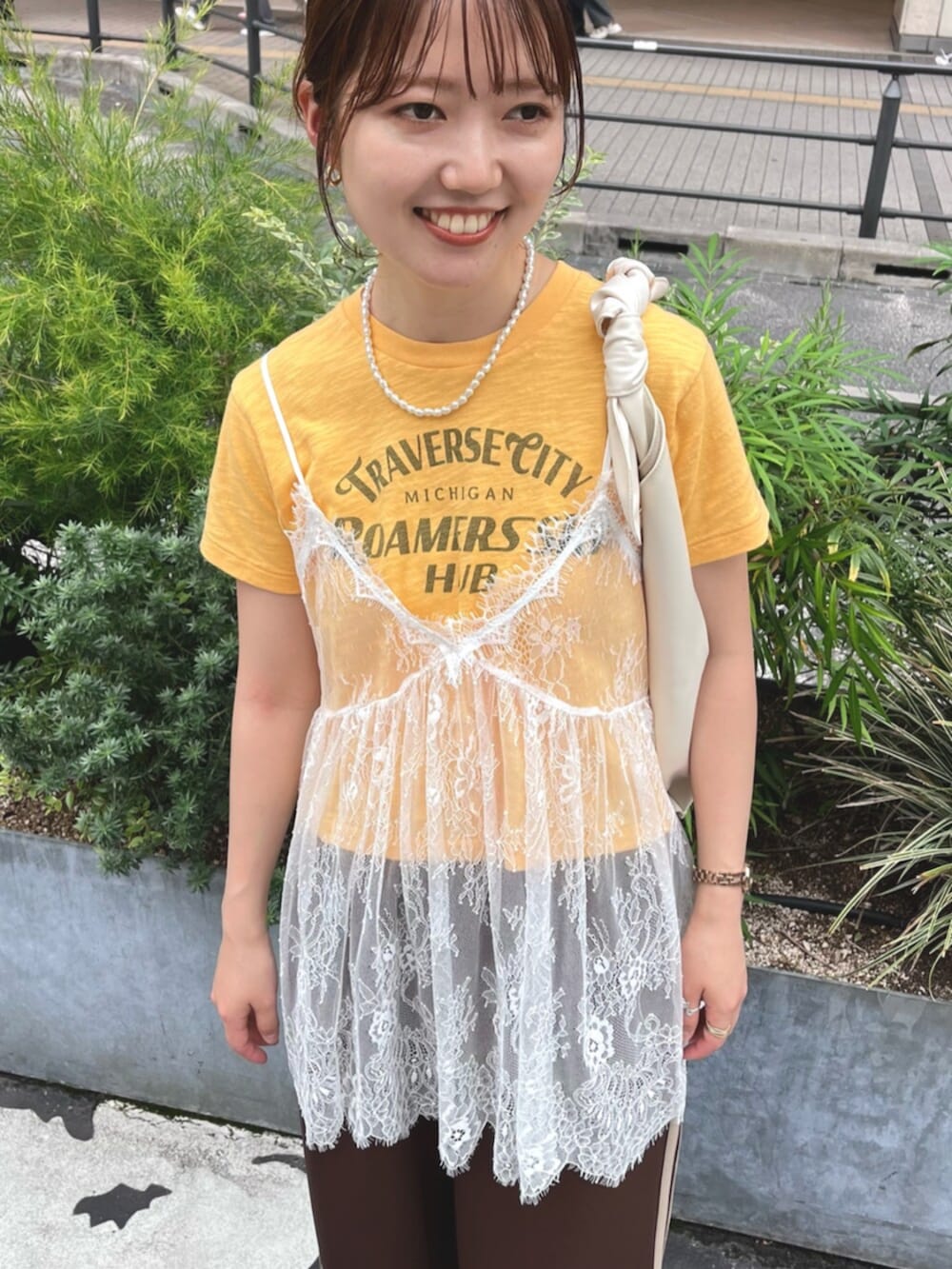 イエロー系のTシャツ/カットソー、ホワイト系のキャミソール、ホワイト系のハンドバッグを着用したレディースの夏コーディネートの6枚目の写真