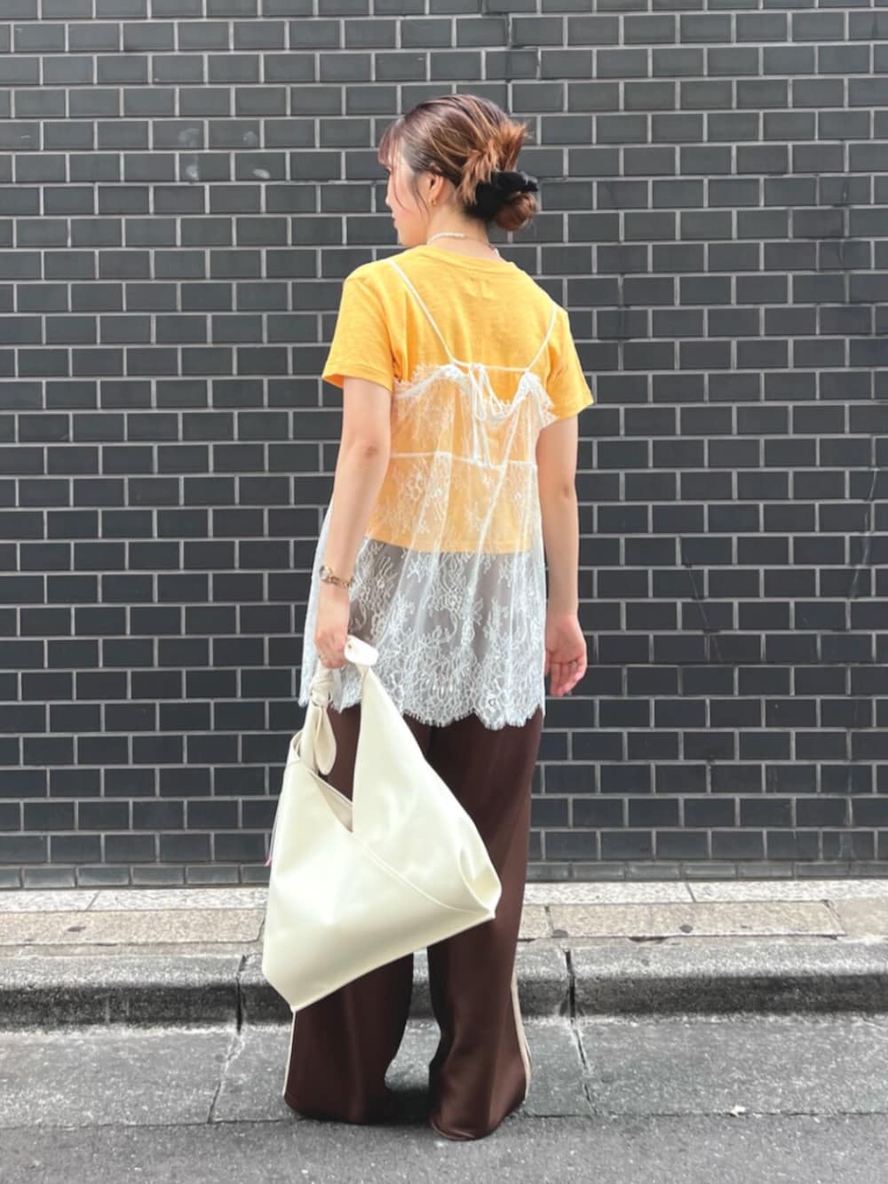 イエロー系のTシャツ/カットソー、ホワイト系のキャミソール、ホワイト系のハンドバッグを着用したレディースの夏コーディネートの4枚目の写真