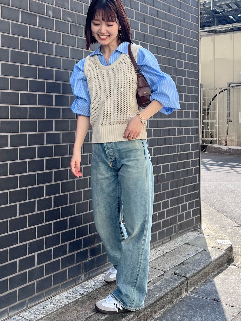 ブルー系のデニムパンツ、ホワイト系のニット/セーター、ブルー系のシャツ/ブラウスを着用したレディースの秋コーディネートの2枚目の写真