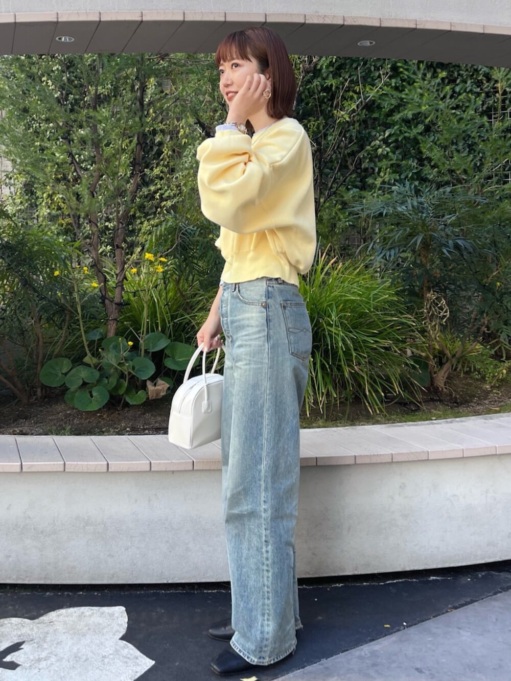 イエロー系のニット/セーター、ホワイト系のボストンバッグ、ブルー系のデニムパンツを着用したレディースの冬コーディネートの2枚目の写真