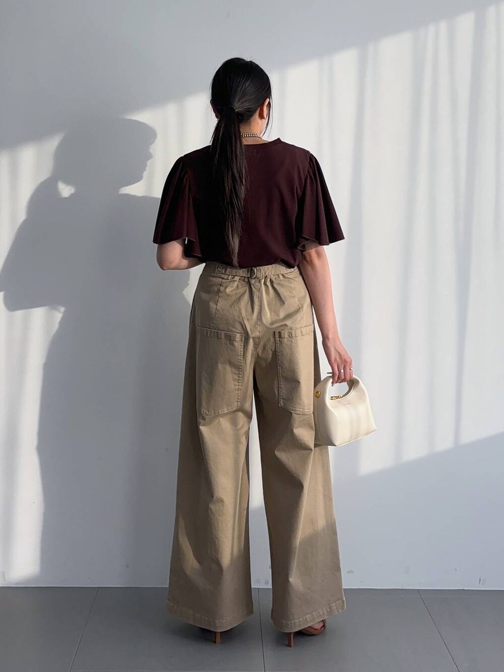 ブラウン系のサンダル、ホワイト系のハンドバッグ、ブラウン系のTシャツ/カットソーを着用したレディースの夏コーディネートの2枚目の写真