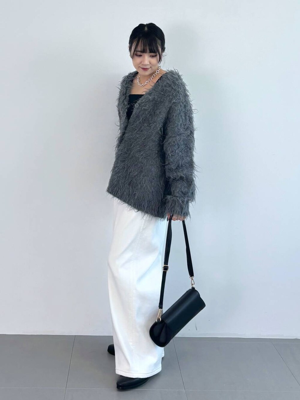 ブラック系のブーツ、ブラック系のタンクトップ、ブラック系のショルダーバッグを着用したレディースの秋コーディネートの3枚目の写真