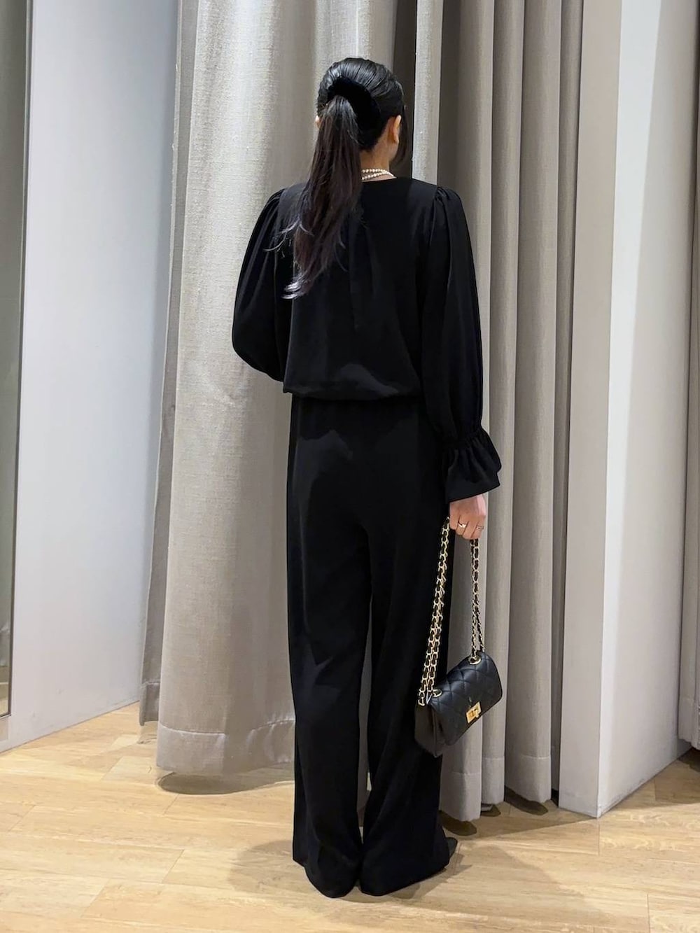 ブラック系のつなぎ/オールインワン、ブラック系のショルダーバッグ、ブラック系のパンプスを着用したレディースの冬コーディネートの3枚目の写真