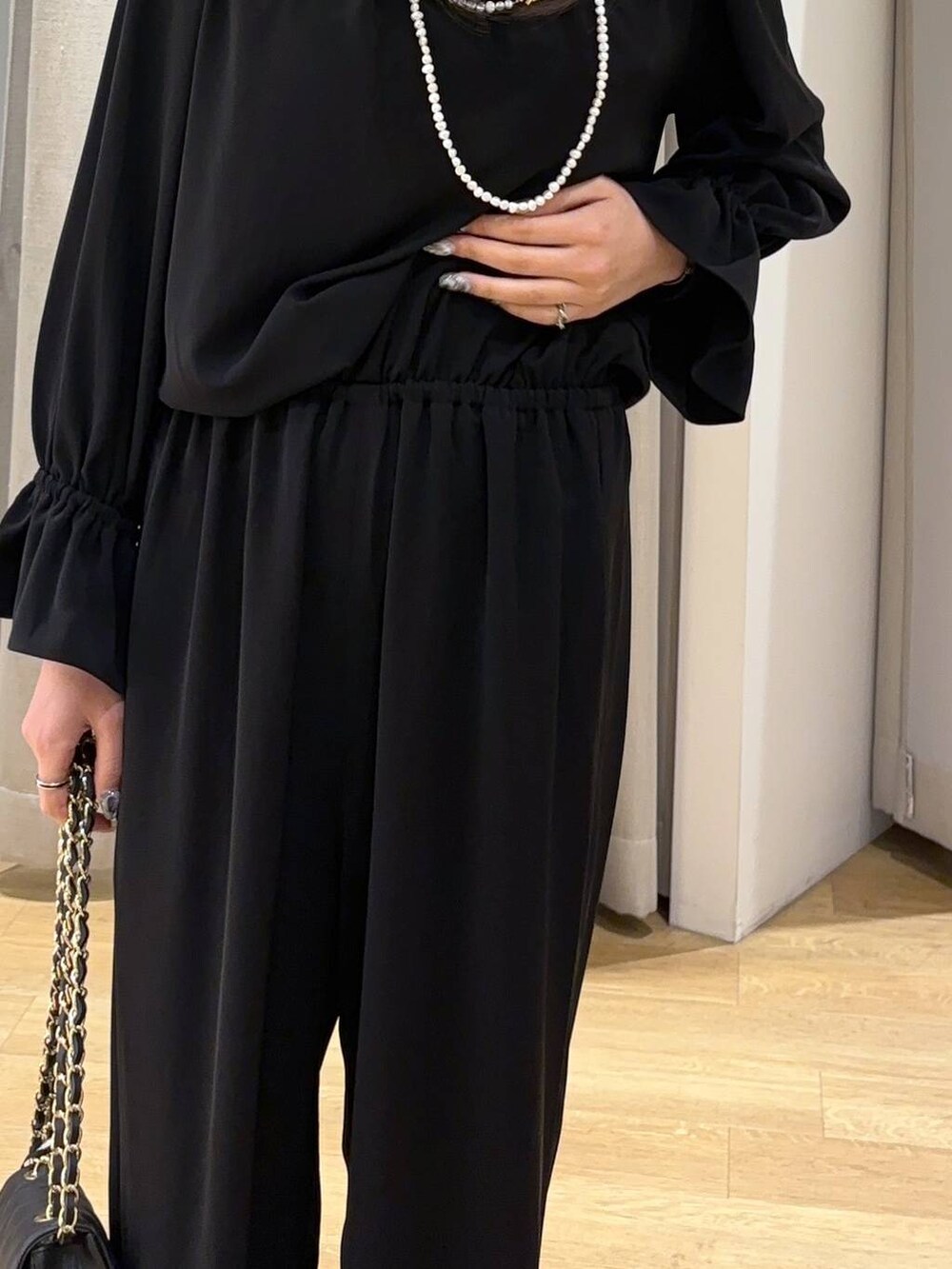 ブラック系のつなぎ/オールインワン、ブラック系のショルダーバッグ、ブラック系のパンプスを着用したレディースの冬コーディネートの2枚目の写真