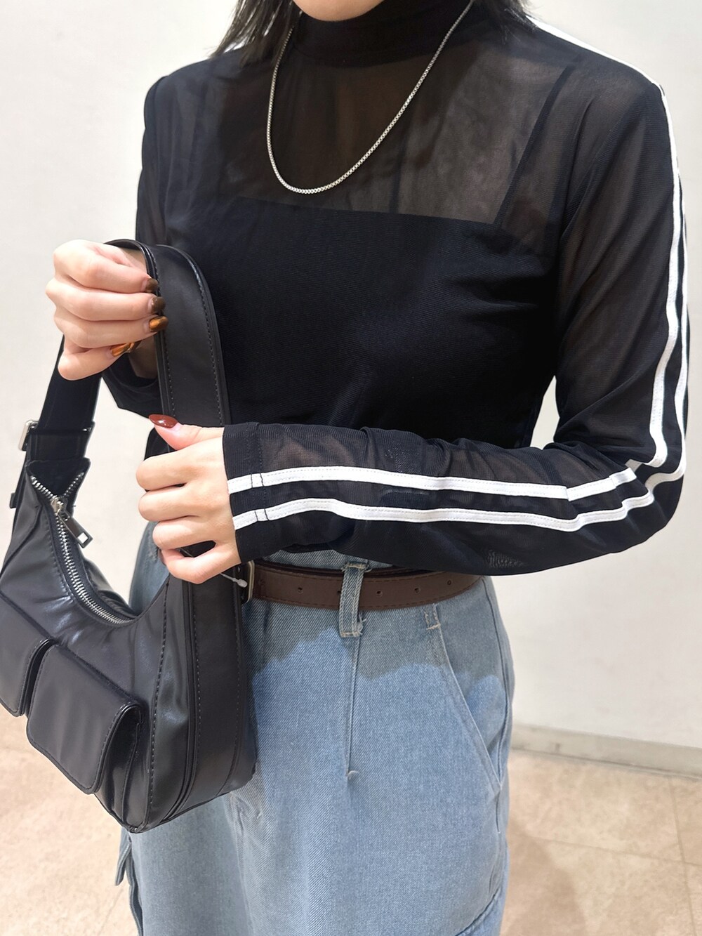 ブラック系のTシャツ/カットソー、ブラック系のショルダーバッグ、ブルー系のデニムスカートを着用したレディースの春コーディネートの6枚目の写真