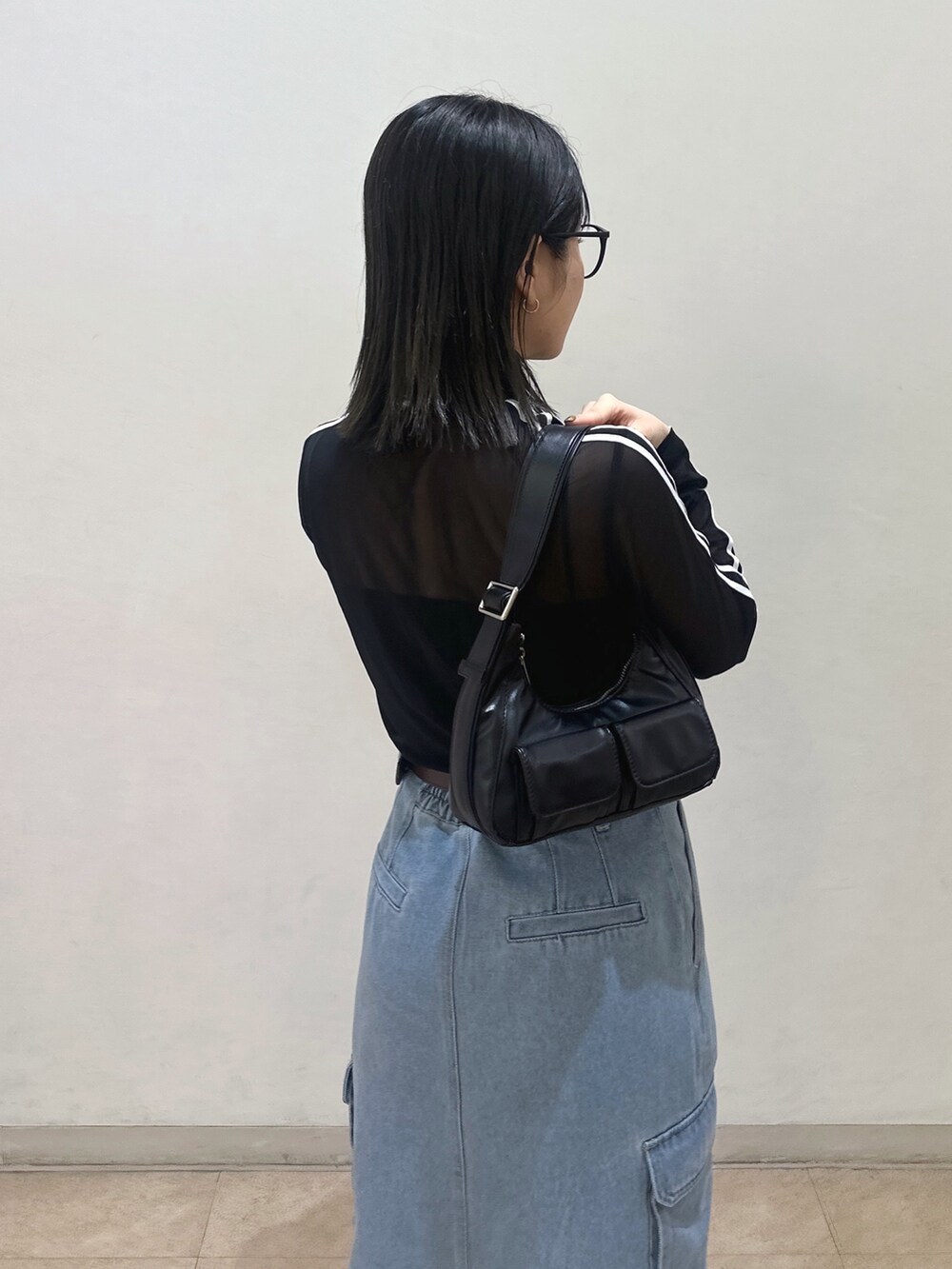 ブラック系のTシャツ/カットソー、ブラック系のショルダーバッグ、ブルー系のデニムスカートを着用したレディースの春コーディネートの4枚目の写真