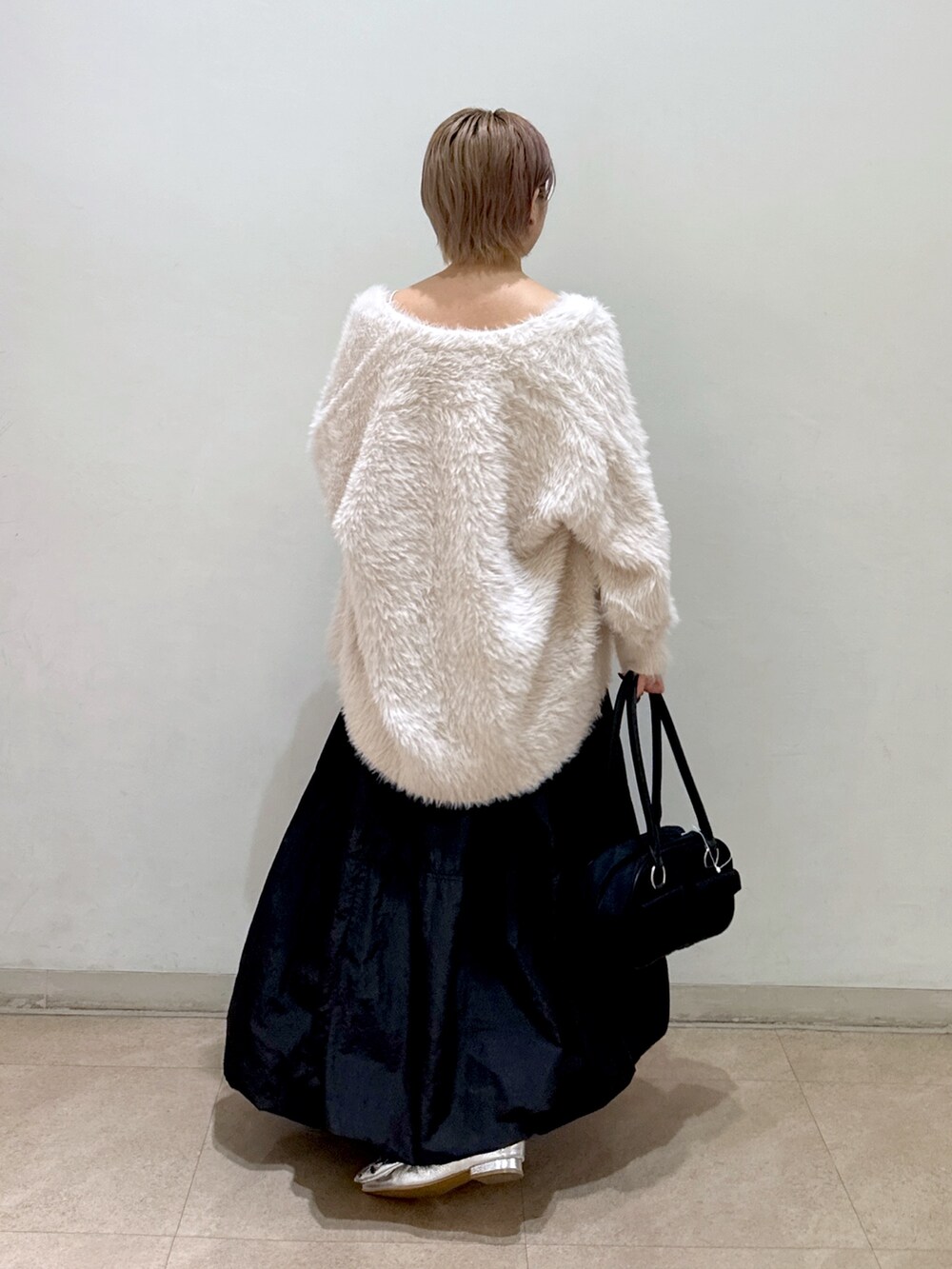 ホワイト系のカーディガン/ボレロ、ブラック系のスカート、ブラック系のトートバッグを着用したレディースの秋コーディネートの2枚目の写真