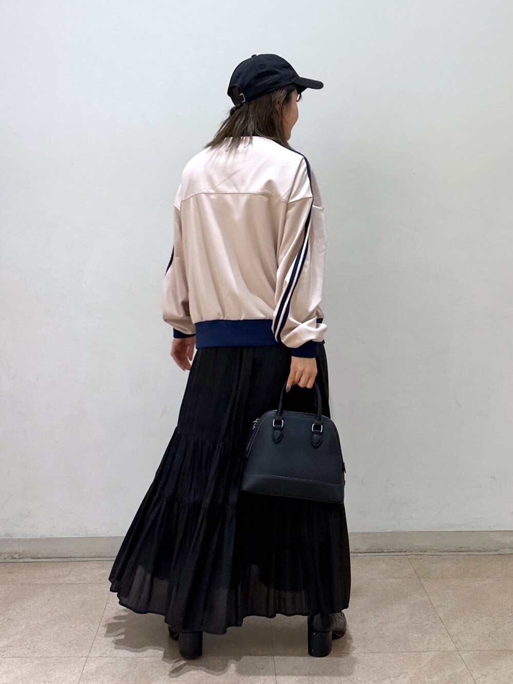 ホワイト系のブルゾン、ブラック系のショルダーバッグ、ブラック系のスカートを着用したレディースの春コーディネートの3枚目の写真