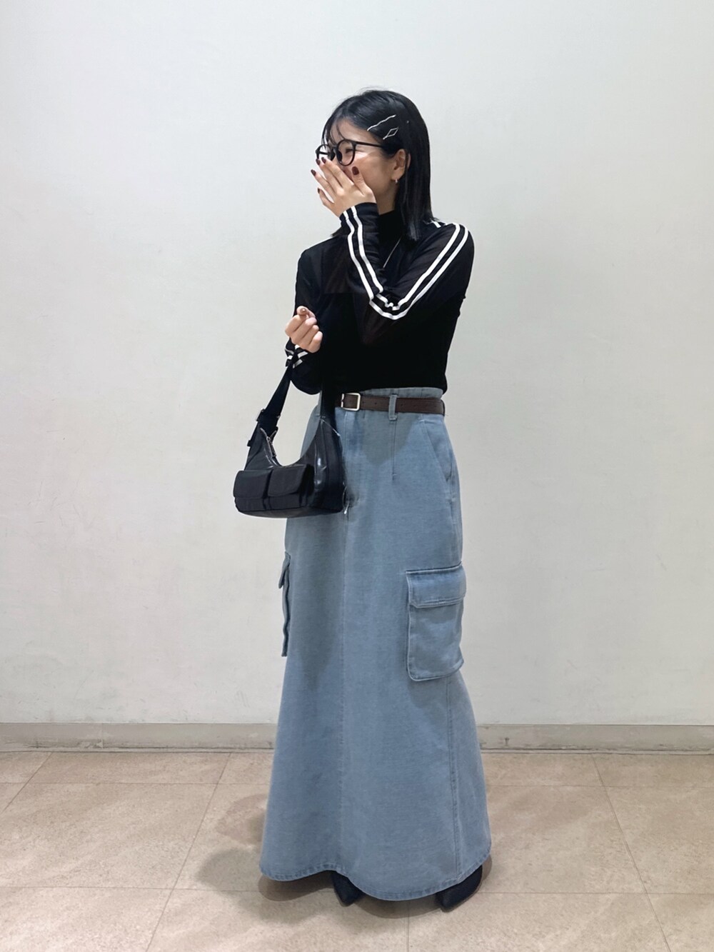 ブラック系のTシャツ/カットソー、ブラック系のショルダーバッグ、ブルー系のデニムスカートを着用したレディースの春コーディネートの2枚目の写真