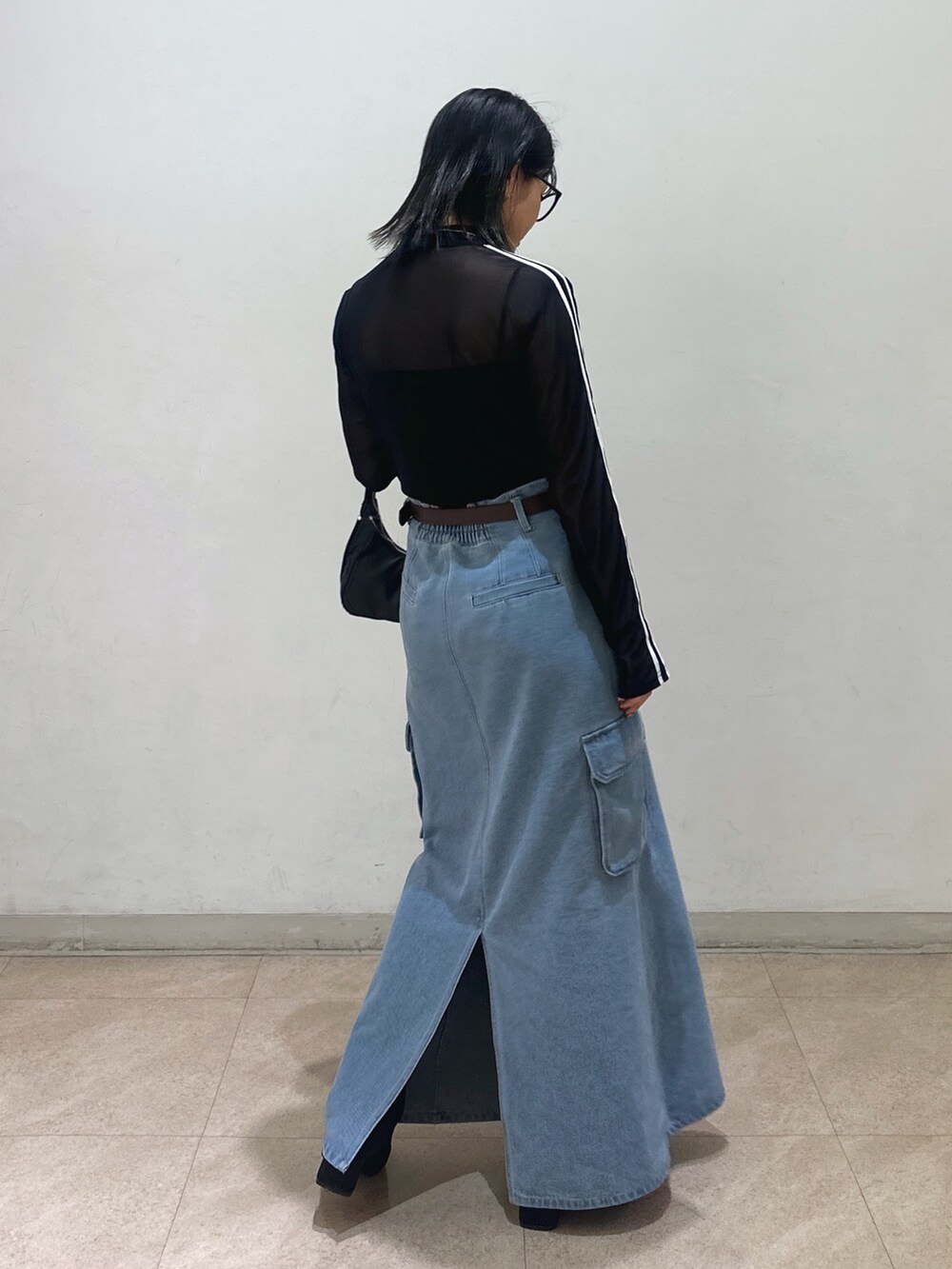 ブラック系のTシャツ/カットソー、ブラック系のショルダーバッグ、ブルー系のデニムスカートを着用したレディースの春コーディネートの3枚目の写真