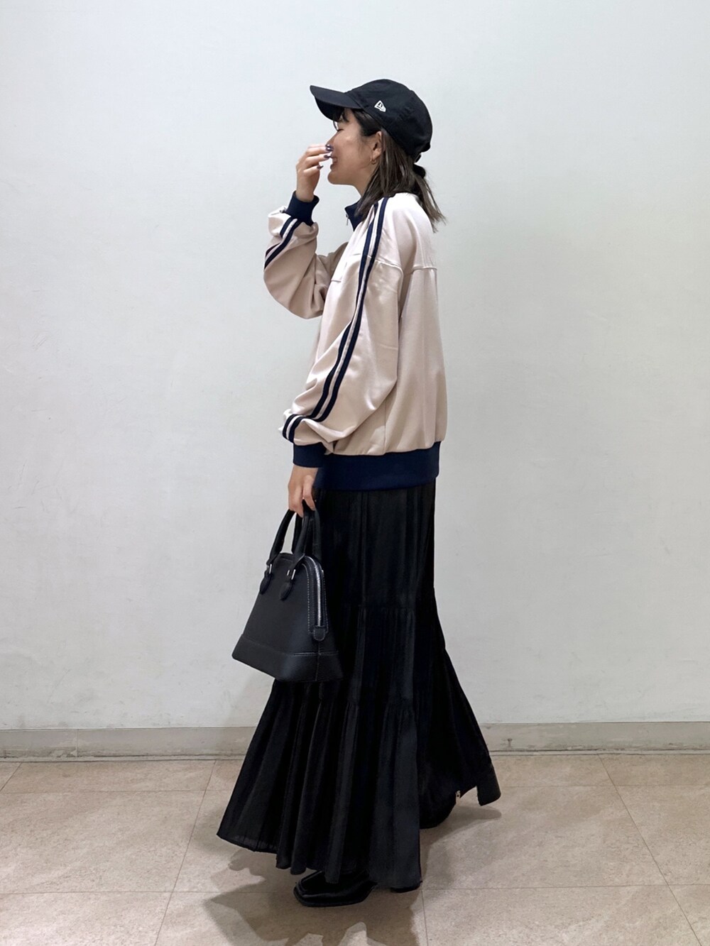 ホワイト系のブルゾン、ブラック系のショルダーバッグ、ブラック系のスカートを着用したレディースの春コーディネートの2枚目の写真