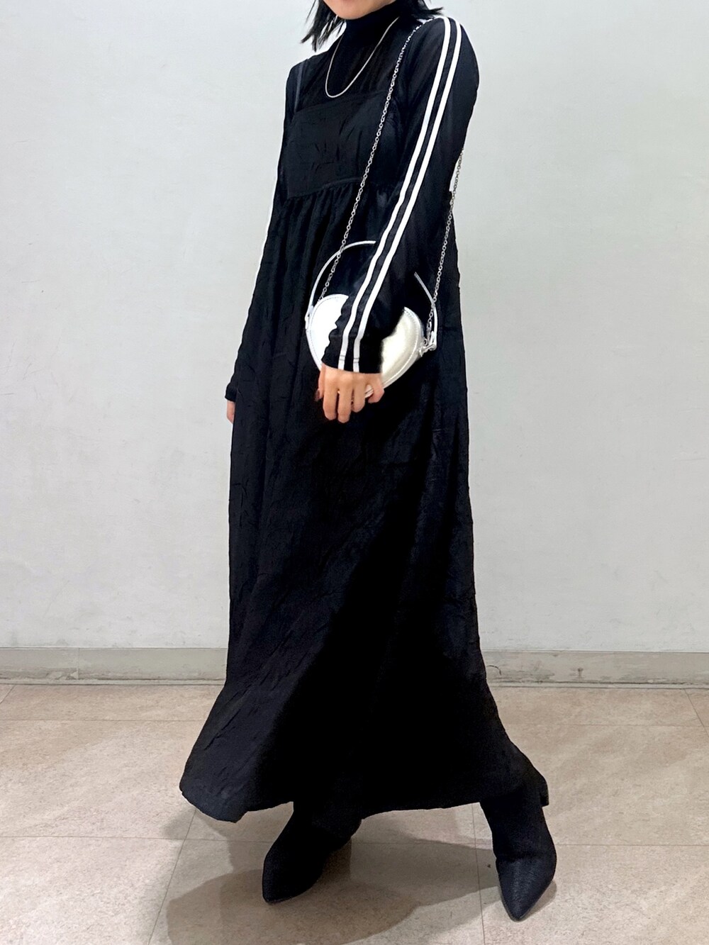 ベージュ系のトレンチコート、ブラック系のワンピース、ブラック系のTシャツ/カットソーを着用したレディースの春コーディネートの3枚目の写真