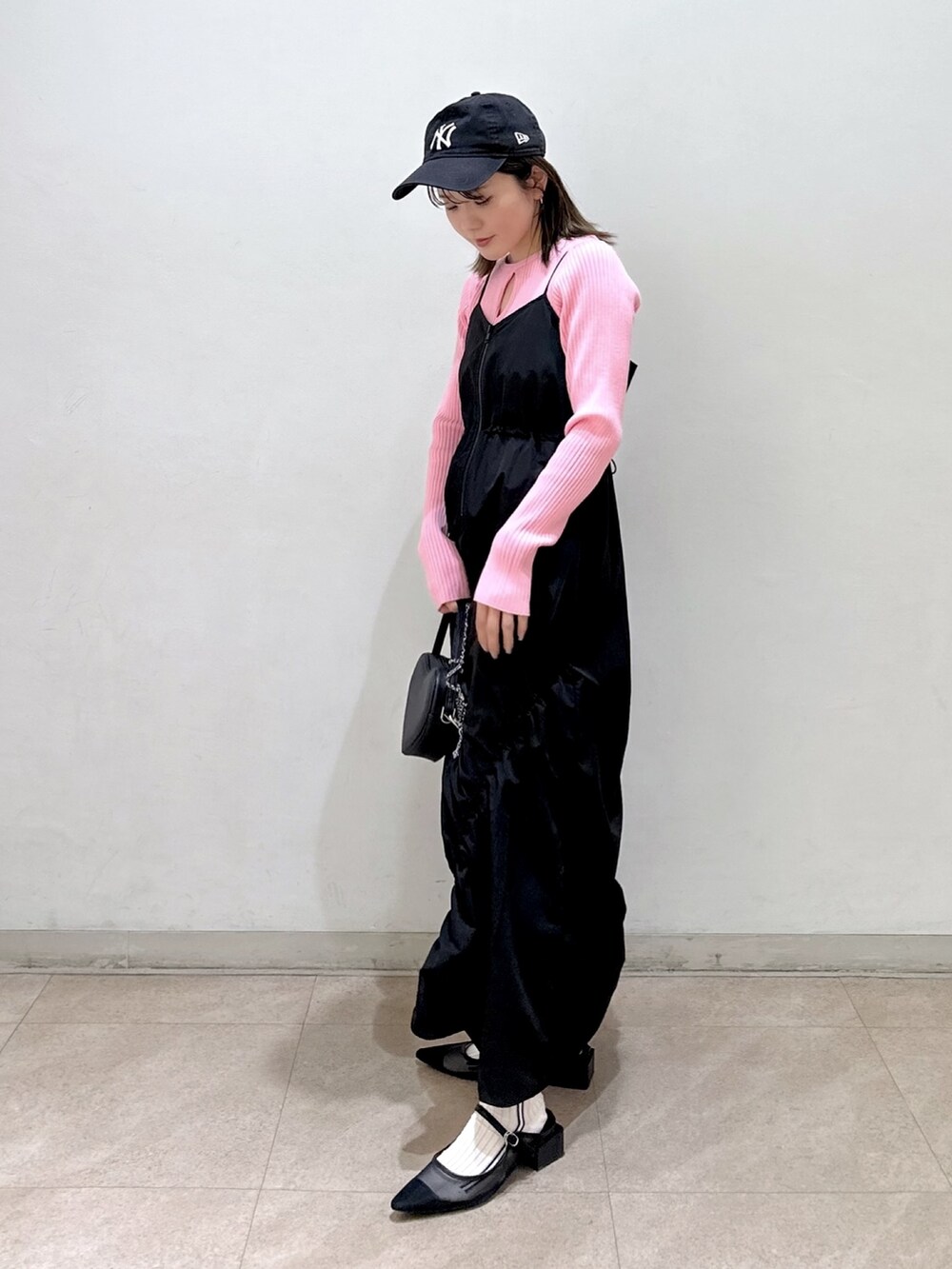 ピンク系のニット/セーター、ブラック系のワンピース、ブラック系のショルダーバッグを着用したレディースの春コーディネートの2枚目の写真