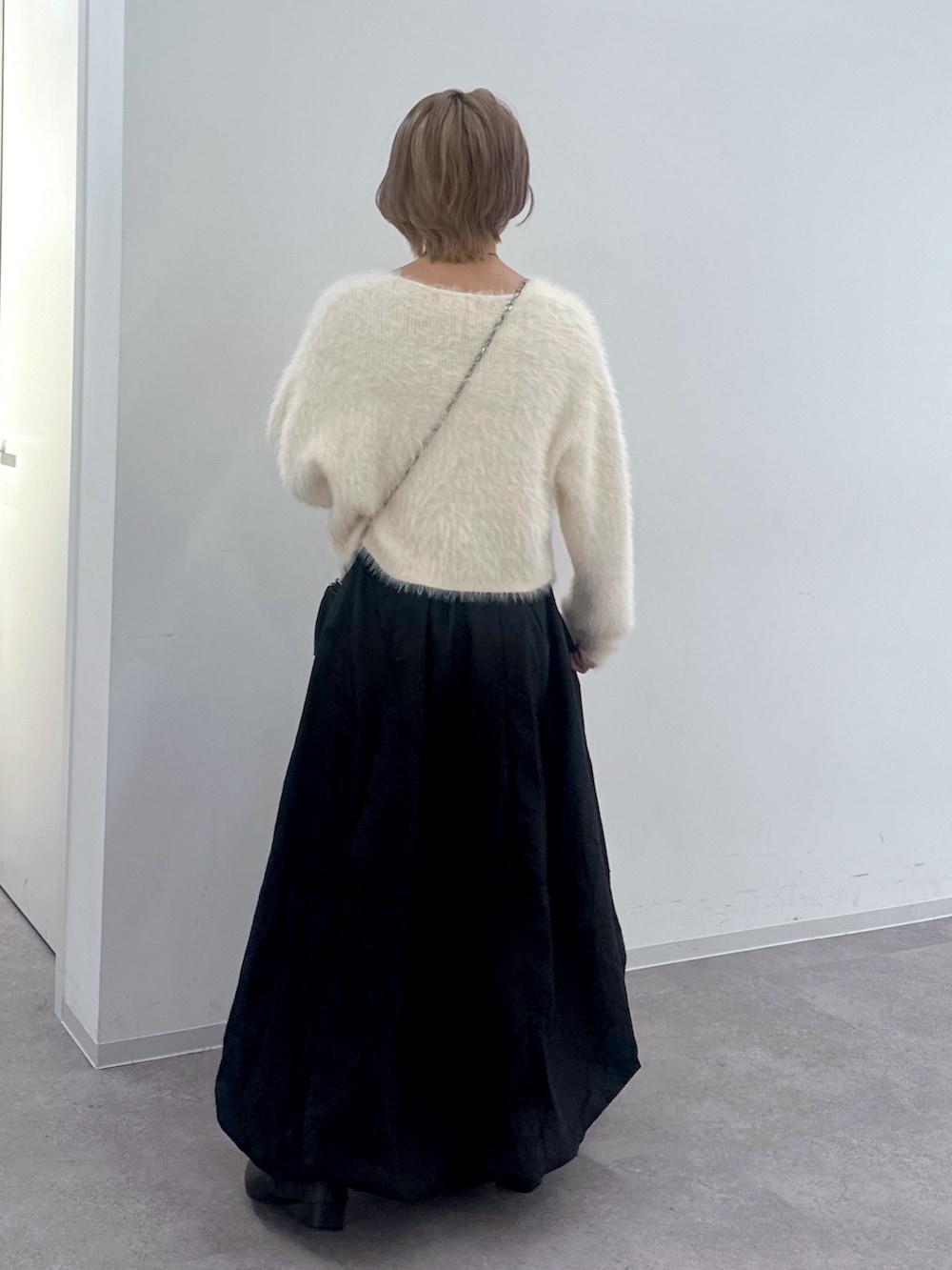 ホワイト系のカーディガン/ボレロ、ブラック系のスカート、ブラック系のハンドバッグを着用したレディースの秋コーディネートの2枚目の写真