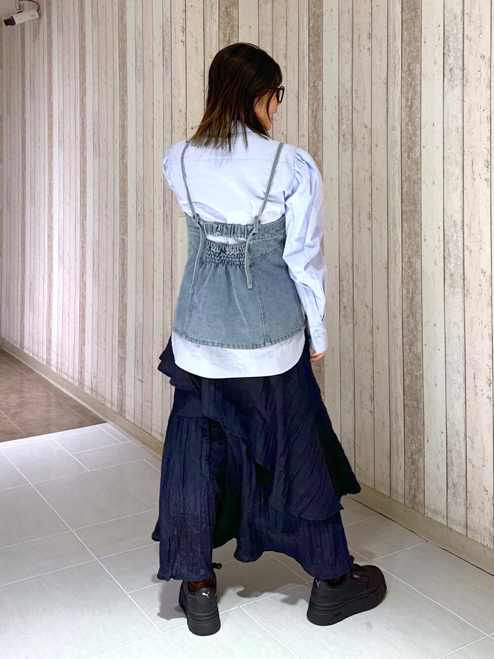 ブルー系のシャツ/ブラウス、ブルー系のベスト、ブラック系のスカートを着用したレディースの春コーディネートの3枚目の写真