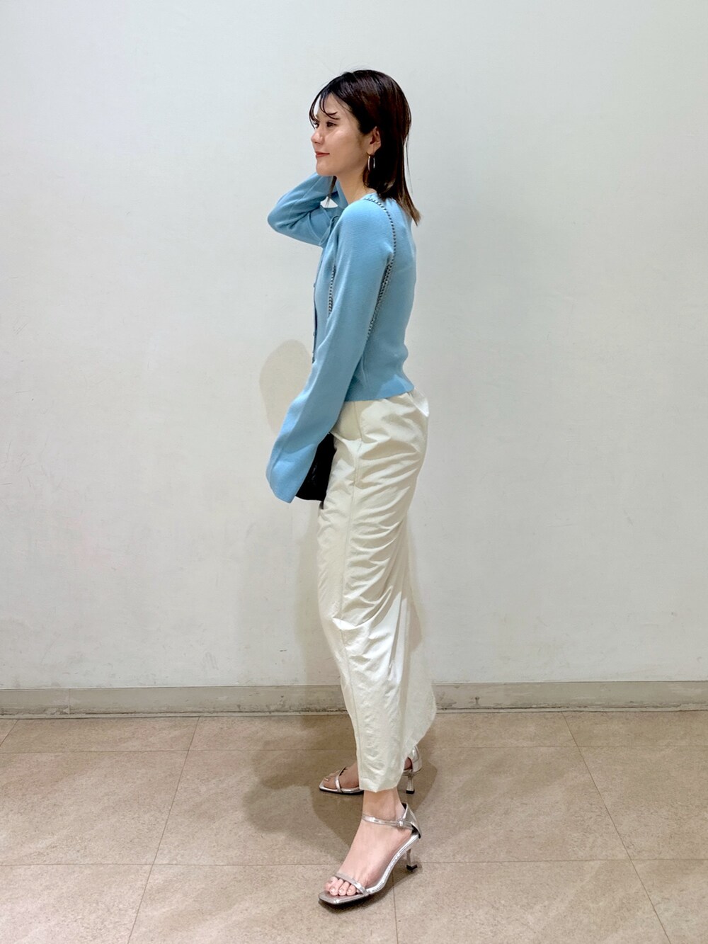 ブルー系のニット/セーター、ベージュ系のスカート、ブラック系のショルダーバッグを着用したレディースの春コーディネートの2枚目の写真