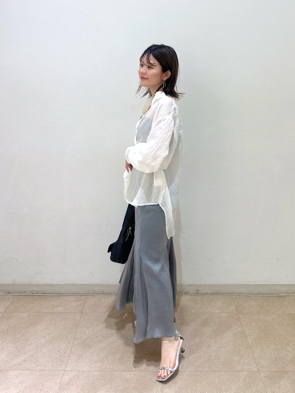ホワイト系のシャツ/ブラウス、グレー系のスカート、ブラック系のキャミソールを着用したレディースの春コーディネートの2枚目の写真