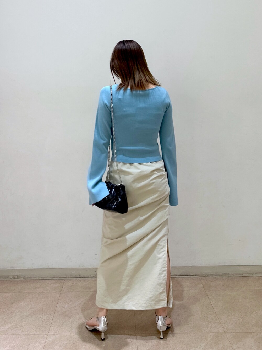 ブルー系のニット/セーター、ベージュ系のスカート、ブラック系のショルダーバッグを着用したレディースの春コーディネートの3枚目の写真