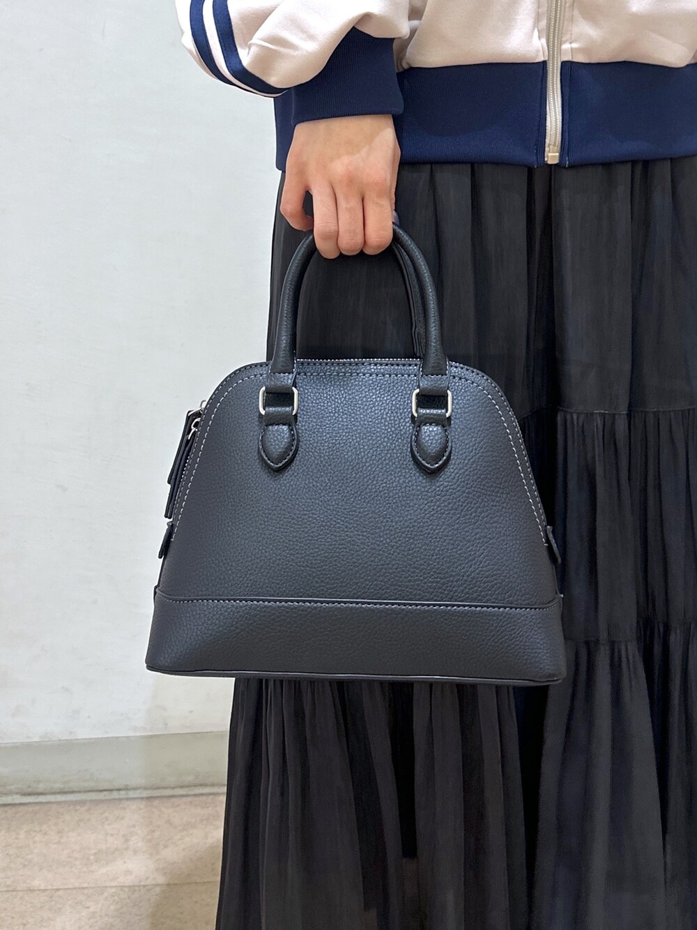 ホワイト系のブルゾン、ブラック系のショルダーバッグ、ブラック系のスカートを着用したレディースの春コーディネートの4枚目の写真