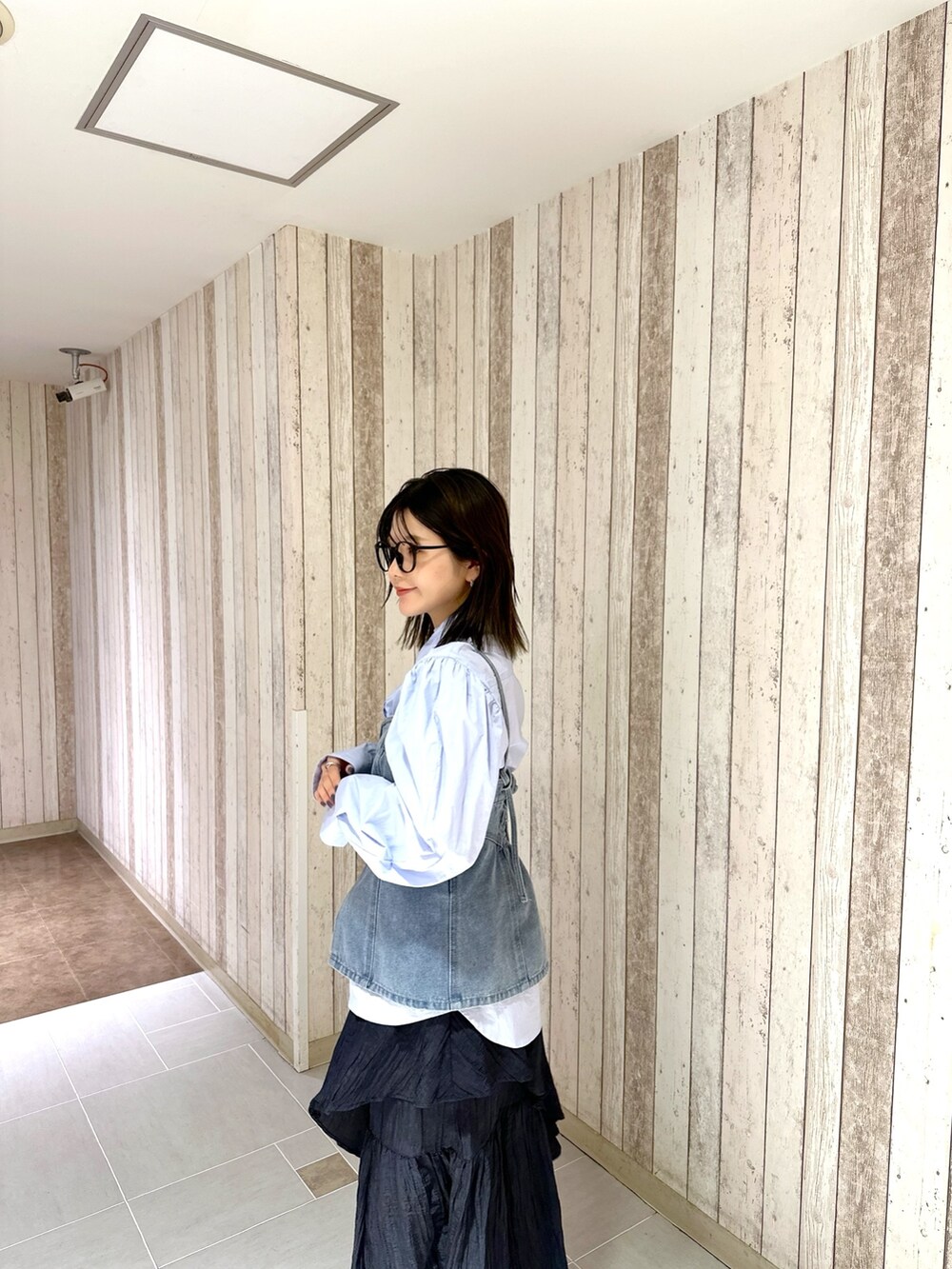 ブルー系のシャツ/ブラウス、ブルー系のベスト、ブラック系のスカートを着用したレディースの春コーディネートの4枚目の写真