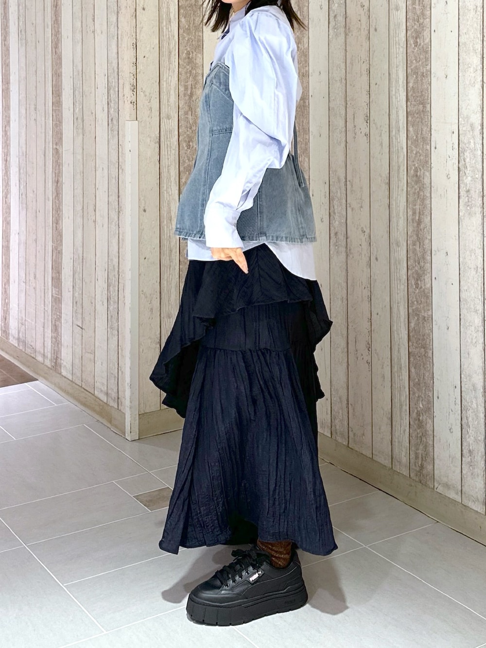 ブルー系のシャツ/ブラウス、ブルー系のベスト、ブラック系のスカートを着用したレディースの春コーディネートの2枚目の写真