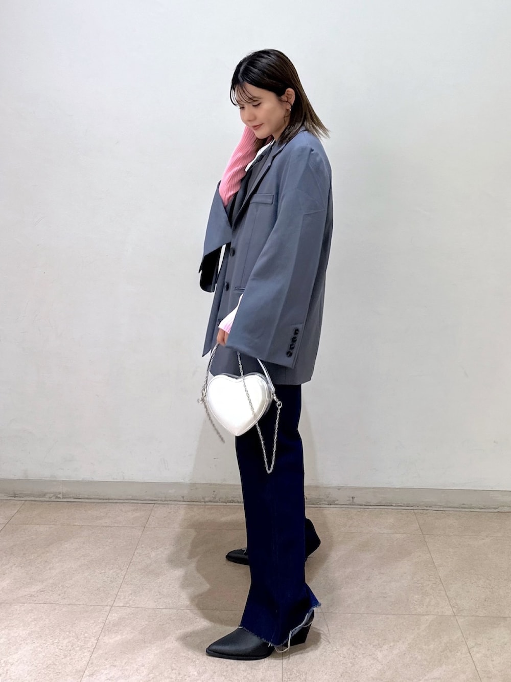 グレー系のテーラードジャケット、ピンク系のニット/セーター、ブラック系のパンプスを着用したレディースの春コーディネートの2枚目の写真