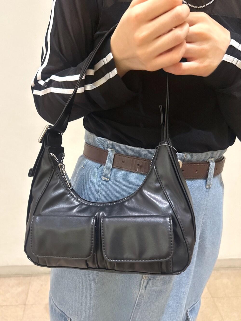 ブラック系のTシャツ/カットソー、ブラック系のショルダーバッグ、ブルー系のデニムスカートを着用したレディースの春コーディネートの7枚目の写真