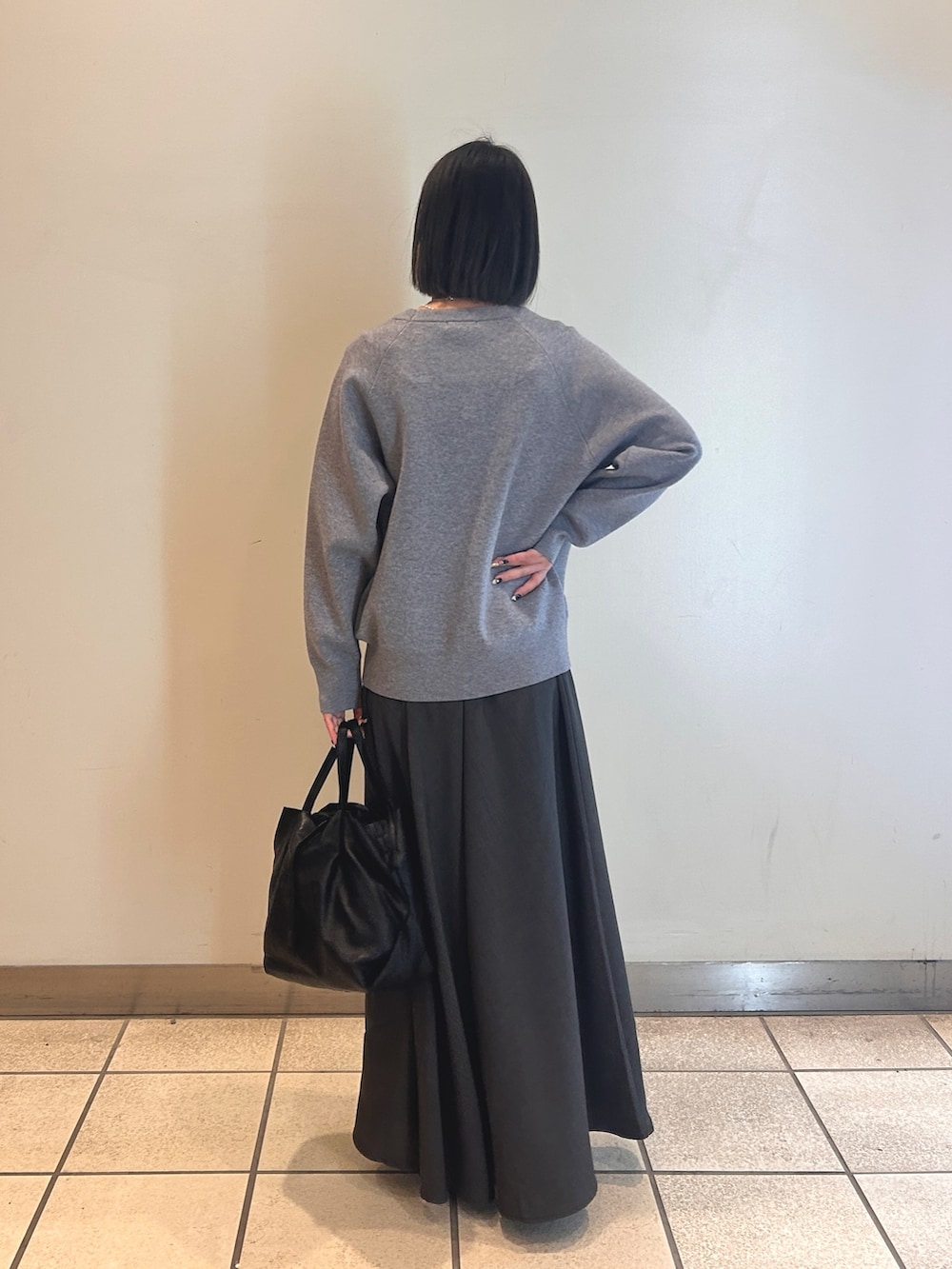 グレー系のワンピース、ブラック系のショルダーバッグ、シルバー系のネックレスを着用したレディースの冬コーディネートの2枚目の写真