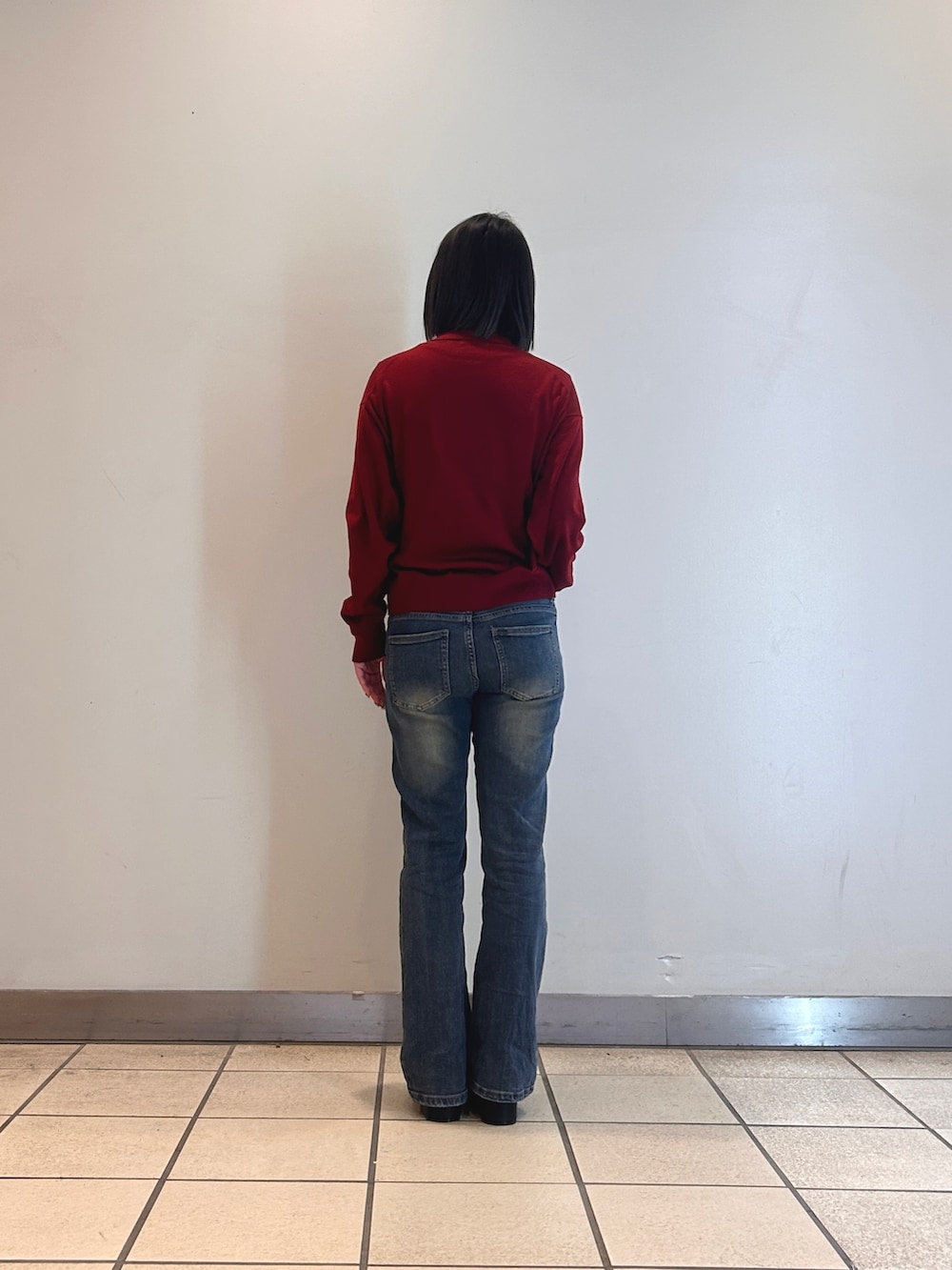 レッド系のカーディガン/ボレロ、ブルー系のデニムパンツ、ブラック系のブーツを着用したレディースの冬コーディネートの2枚目の写真