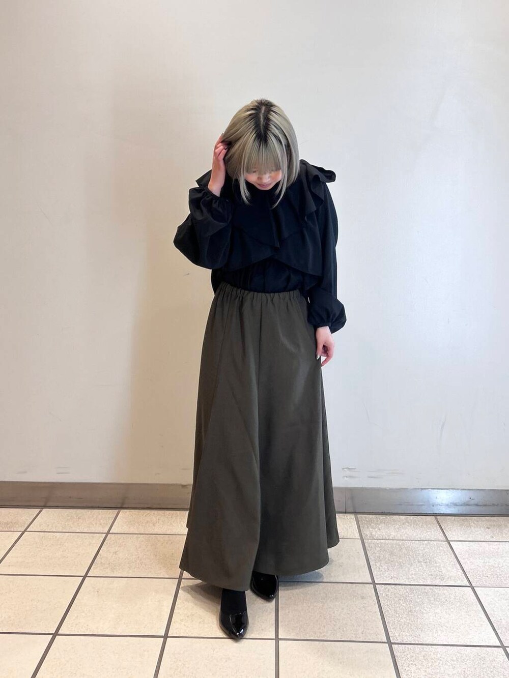 ブラウン系のスカート、ブラック系のシャツ/ブラウスを着用したレディースの春コーディネートの2枚目の写真