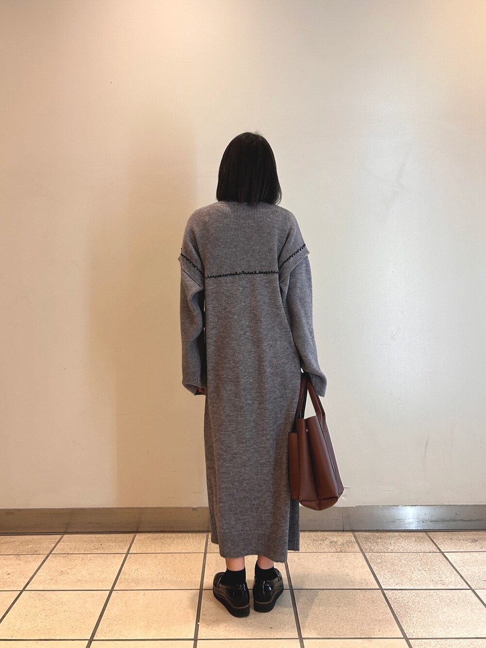 グレー系のワンピース、ブラウン系のショルダーバッグを着用したレディースの冬コーディネートの3枚目の写真