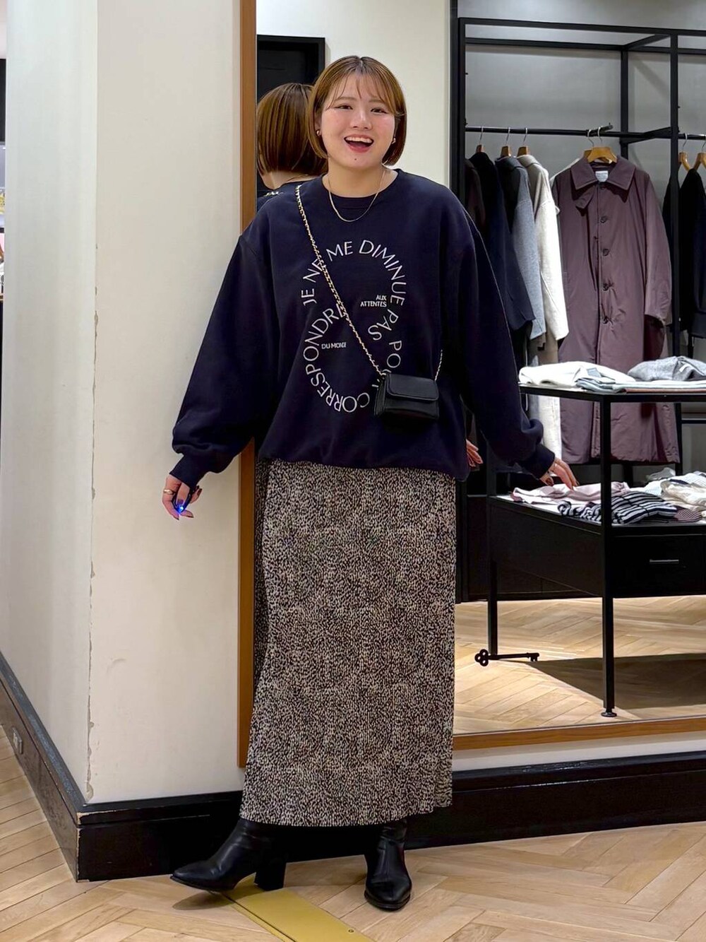 ブラック系のブーツ、ベージュ系のスカート、ブルー系のスウェットを着用したレディースの秋コーディネートの3枚目の写真