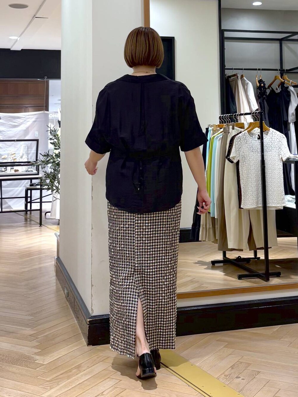 ブラック系のサンダル、ホワイト系のスカート、ブラック系のシャツ/ブラウスを着用したレディースの夏コーディネートの7枚目の写真