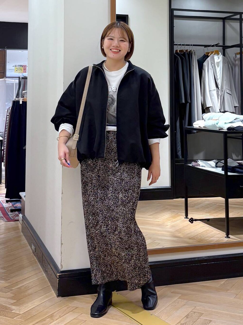 ブラウン系のスカート、ブラック系のブルゾン、ブラック系のブーツを着用したレディースの秋コーディネートの3枚目の写真